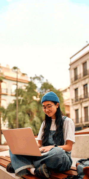 Photo of a female student sitting in front of a building, looking at laptop. Animated text says: "Your views, your NSS".